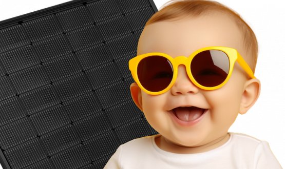 Lächelndes Baby mit einer gelben Sonnenbrille. Im Hintergrund sind Photovolthaikplatten Lächelndes Baby mit einer gelben Sonnenbrille. Im Hintergrund sind Photovolthaikplatten